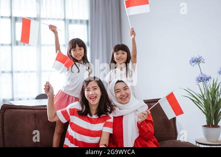 mother and daughter celebrating indonesian independence day at home wearing red and white with indonesia flag Stock Photo