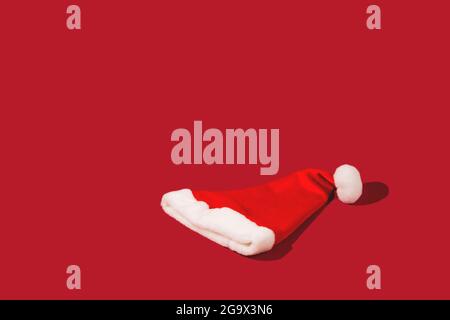 Red Santa Claus hat on monohomic background. Minimalistic Christmas composition. Creative background with copy space. Stock Photo