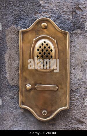 Old fashioned brass door bell intercom on wall in Lucca in Italy Stock Photo