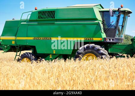 John Deere combine harvester in ripe rye field on a beautiful day of late summer. Salo, Finland. July 25, 2021. Stock Photo