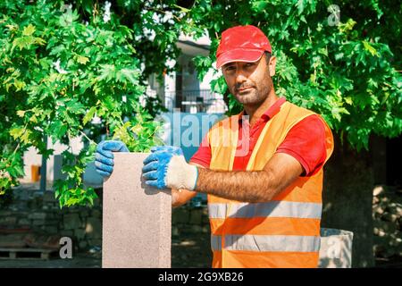 Turkish pavement construction worker holds a big tile of pavement stone. Stock Photo