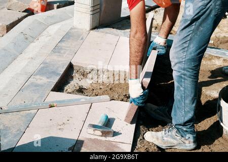 Hands of a Turkish pavement construction worker installing a big tile and builds a sidewalk. Stock Photo