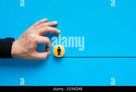 Firing, job loss and unemployment concept. Employer hand is about to flick the ball with the employee icon on the line. Stock Photo