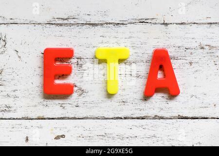 Color alphabet in word ETA (Abbbreviation of Estimated Time of Arrival) on grunge old white wood background Stock Photo