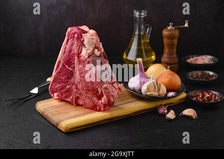 Raw porterhouse steak with ingredients for cooking on wooden log Stock Photo
