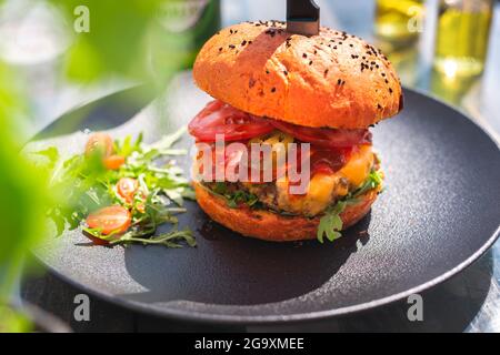 Burger with beef and vegetables, vegetable salad. Fast food. The cook cooks and serves an appetizing dish. The finished dish served on a plate. Servin Stock Photo