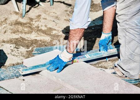 Turkish pavement construction worker using a water level tool for balancing the tiles. Stock Photo