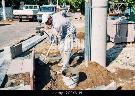 Worker using a shovel at the pavement construction site. Stock Photo