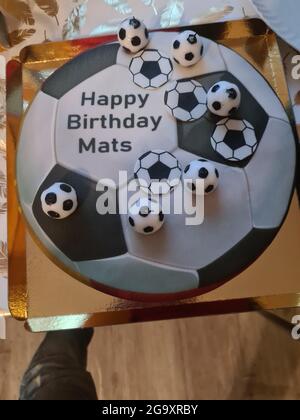Funny and lovely sporty birthday cake. Design with the soccer field. Shoes, buildings, sports day. Cake, cream. green field. Birthday cake for a sport