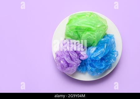 Plate with crumpled bags on color background. Environment pollution concept Stock Photo