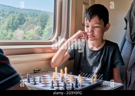 Asian boy thinking a next move in a game of chess Stock Photo