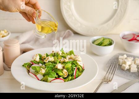 Woman making tasty popcorn salad on table Stock Photo