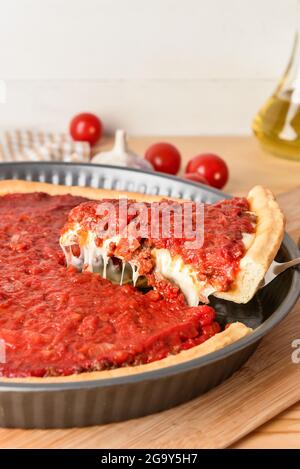 Baking dish with tasty Chicago-style pizza on light background Stock Photo