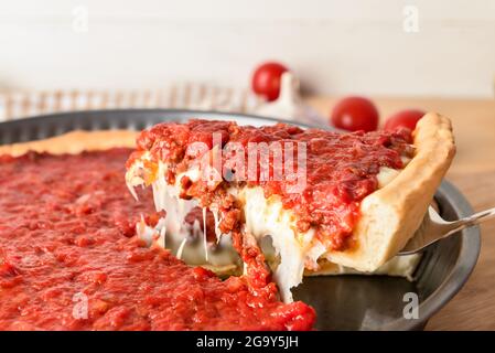 Baking dish with tasty Chicago-style pizza on light background, closeup Stock Photo