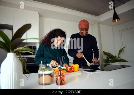 Young mixed race couple cooking food in the kitchen at home. Couple preparing food. High quality photo  Stock Photo
