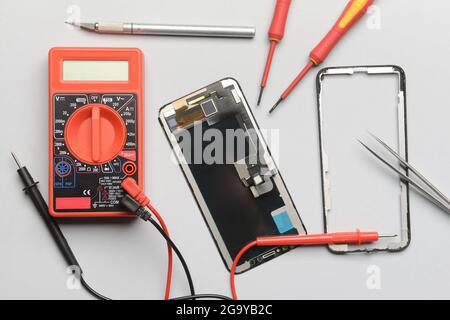 Disassembled mobile phone with technician tools on grey background Stock Photo