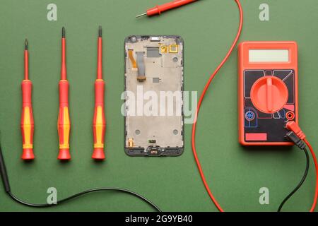 Disassembled mobile phone with technician tools on color background Stock Photo