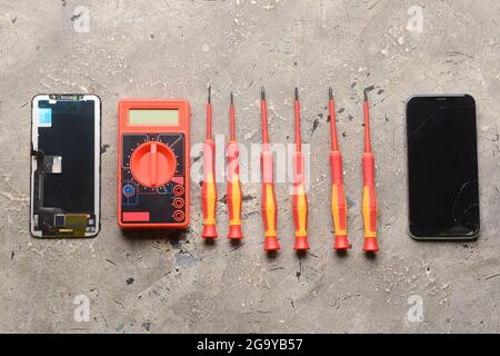 Disassembled mobile phone with technician tools on grunge background Stock Photo