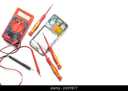 Disassembled mobile phone with multimeter on white background Stock Photo