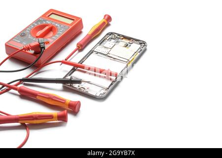 Disassembled mobile phone with multimeter on white background Stock Photo