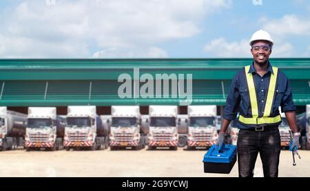 African man technician standing against the truck with holding tool box in hands Stock Photo
