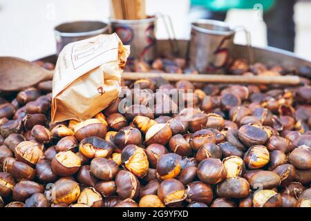 Outdoor chestnut roaster with chestnuts measuring cups and wooden spoon. (Selective focus) Stock Photo