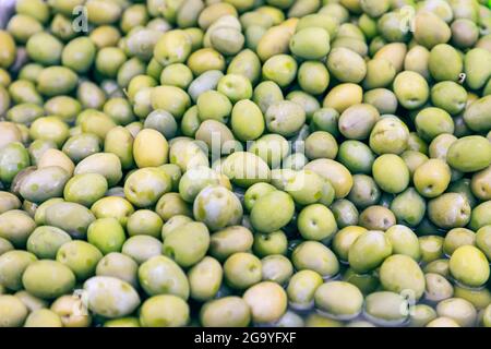 Green pickled olives with red peppers at a grocery market in italy Stock Photo