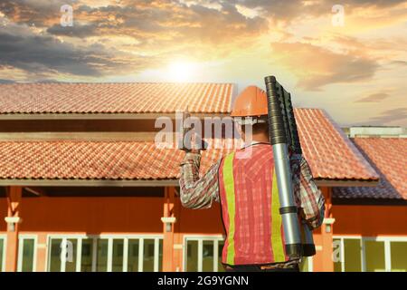 Rear view of a construction worker with tools standing in front of a building, Thailand Stock Photo