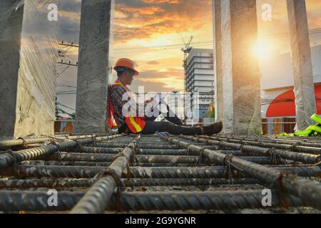 Surveyor on a building site holding a mobile phone and paperwork, Thailand Stock Photo