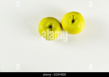 foreground of two green apples with drops on white background viewed from above Stock Photo