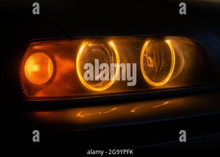 Close-up of orange car headlights in the dark, at night Stock Photo