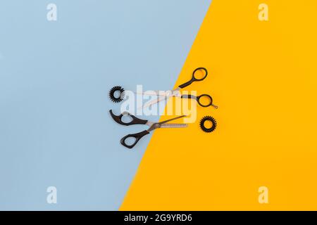 Scissors on the color blue, yellow paper background. Top view. Stock Photo
