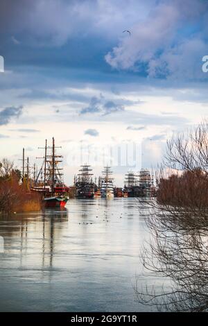 View of Pirate ships at anchor on Sunset in River Manavgat with purple cloud and tree reflection. Stock Photo