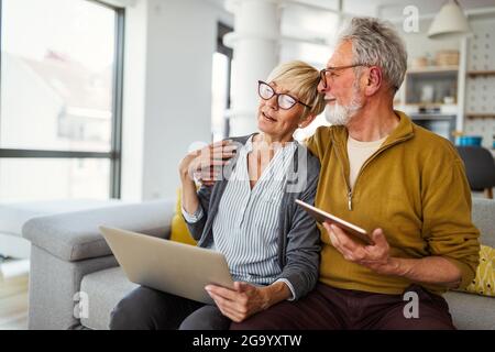 Cheerful senior couple using technology devices and having fun at home Stock Photo