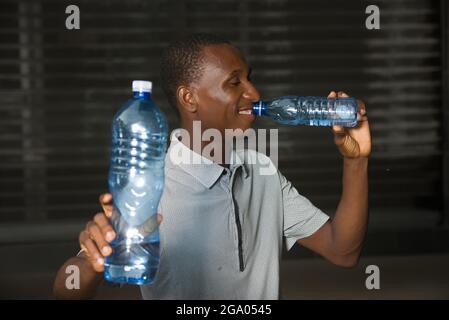 young man standing outdoors go drinking water while smiling. Stock Photo