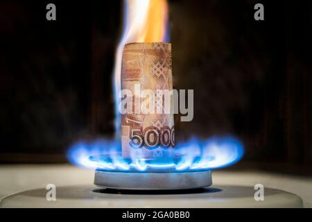 Russian ruble is burning in the fire. concept the rise in the price of gas in Russia. a bill of 5000 rubles burns in a fire on a gas stove. Expensive Stock Photo