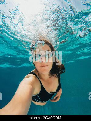 Underwater image of woman blowing swimming in a pool. Stock Photo