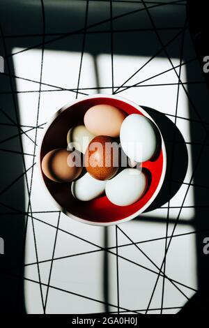 Overhead view of brightly colored eggs in a red bowl