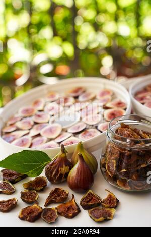 Fresh figs lie on the table next to dried figs in a glass jar on balcony Stock Photo