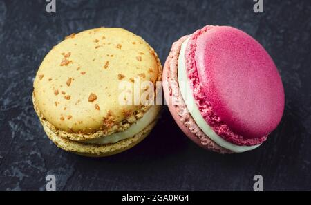 Two sweet French macarons on a dark background. Stock Photo