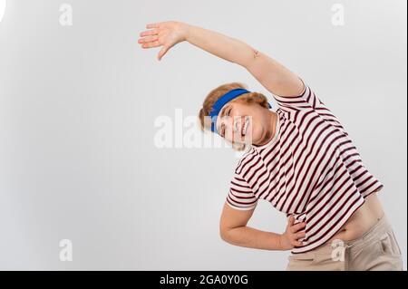 Elderly woman doing fitness doing side bends on a white background. Stock Photo