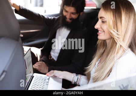 Colleagues working together in modern car using devices and gadgets during creative meeting Stock Photo