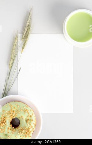 White invitation card mockup flat lay with cup of green matcha tea, pistachio donut and three wheel of rye Stock Photo