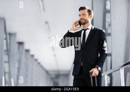 Handsome businessman standing in airport, talking on phone Stock Photo