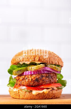 Homemade plant based burger made from sweet potato, black beans and brown rice on a wholegrain brioche bun; copy space Stock Photo