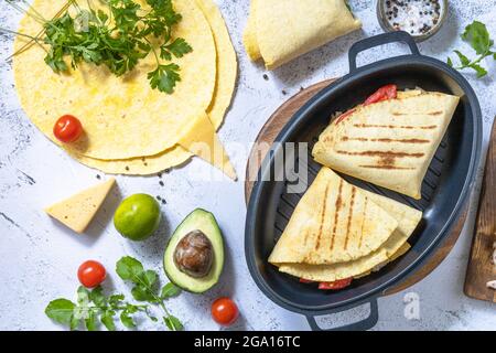 Sandwich chicken Mexican corn tortillas with avocado, arugula and cheese on a gray stone tabletop. Top view flat lay background. Stock Photo