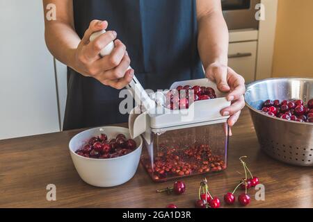 Woman pitting fresh cherries with a cherry stoner Stock Photo
