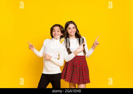 Photo portrait of small kids smiling recommending showing blank space isolated on vivid yellow color background Stock Photo