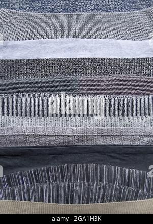 Warm knitted textile stack with the different texture in grey color palette close up Stock Photo