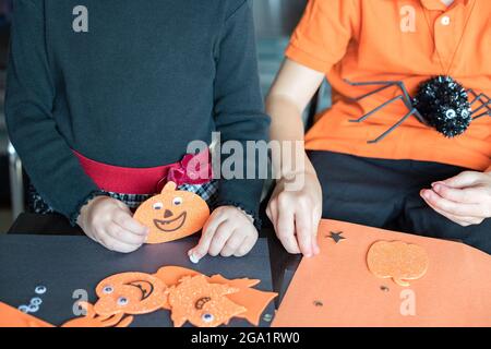 Halloween kids craft preparations. Little children doing crafts at home or school for the holiday party. Stock Photo